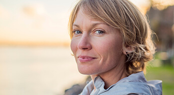 woman sitting by lake smiling